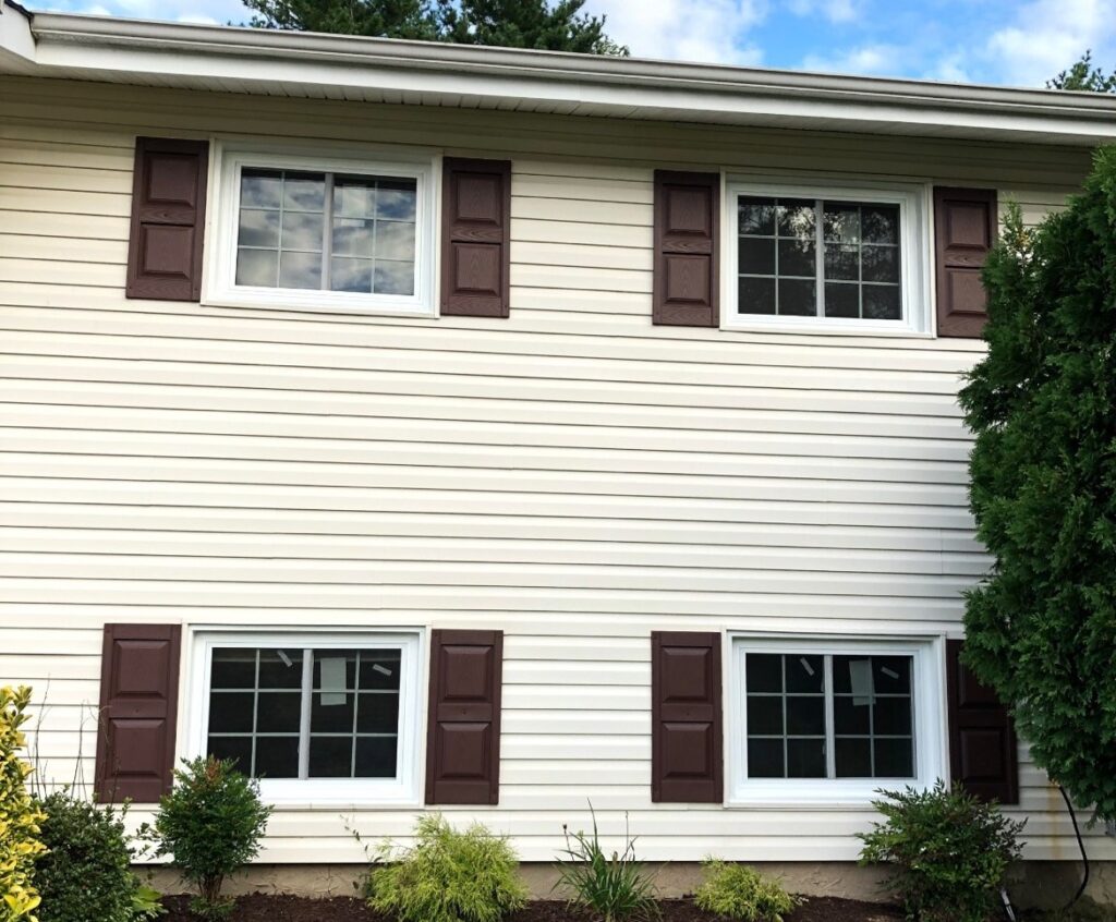 A house with white siding and brown shutters, exuding a classic charm and timeless elegance.